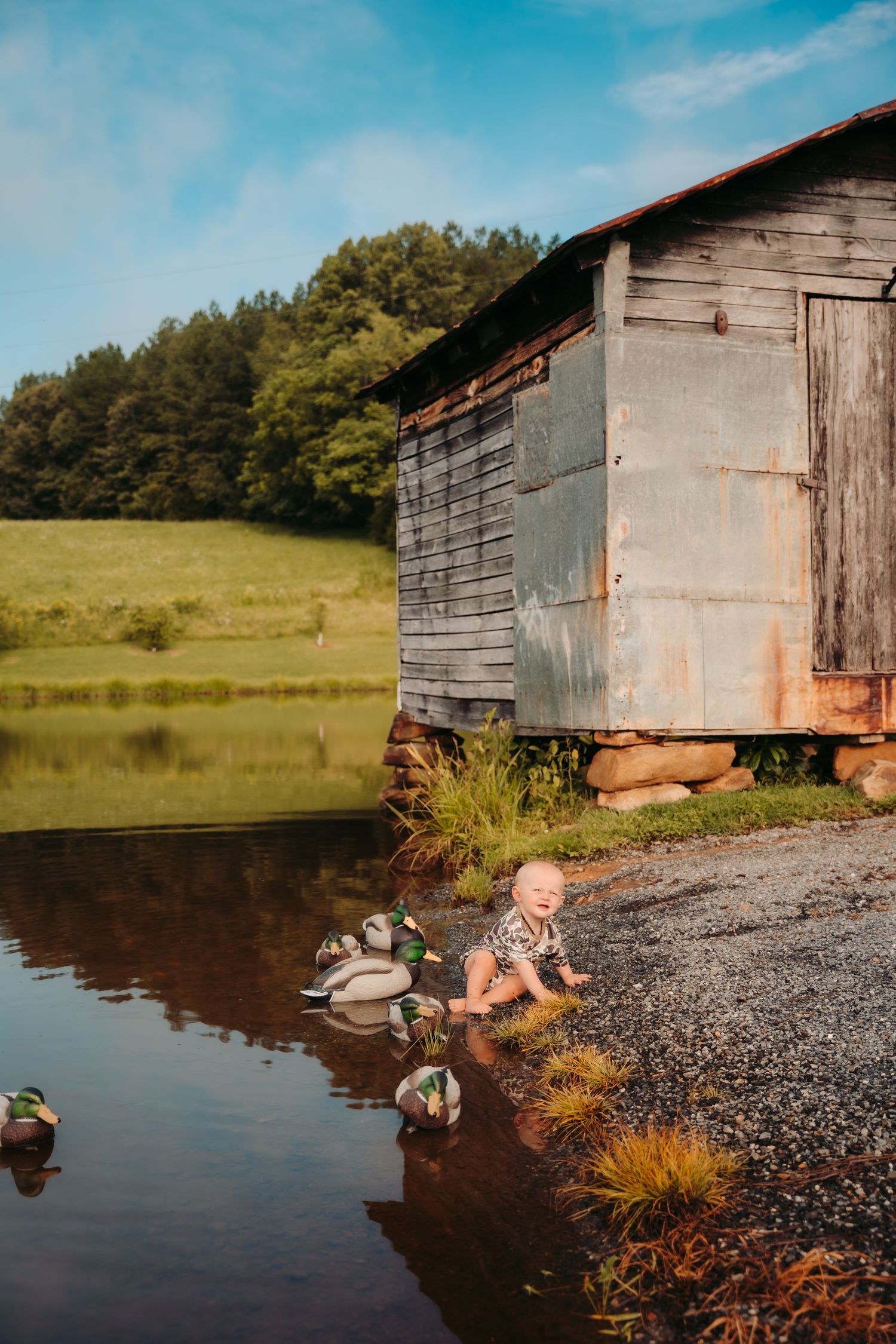 Series of photos showing baby playing near rustic wooden shed by water.