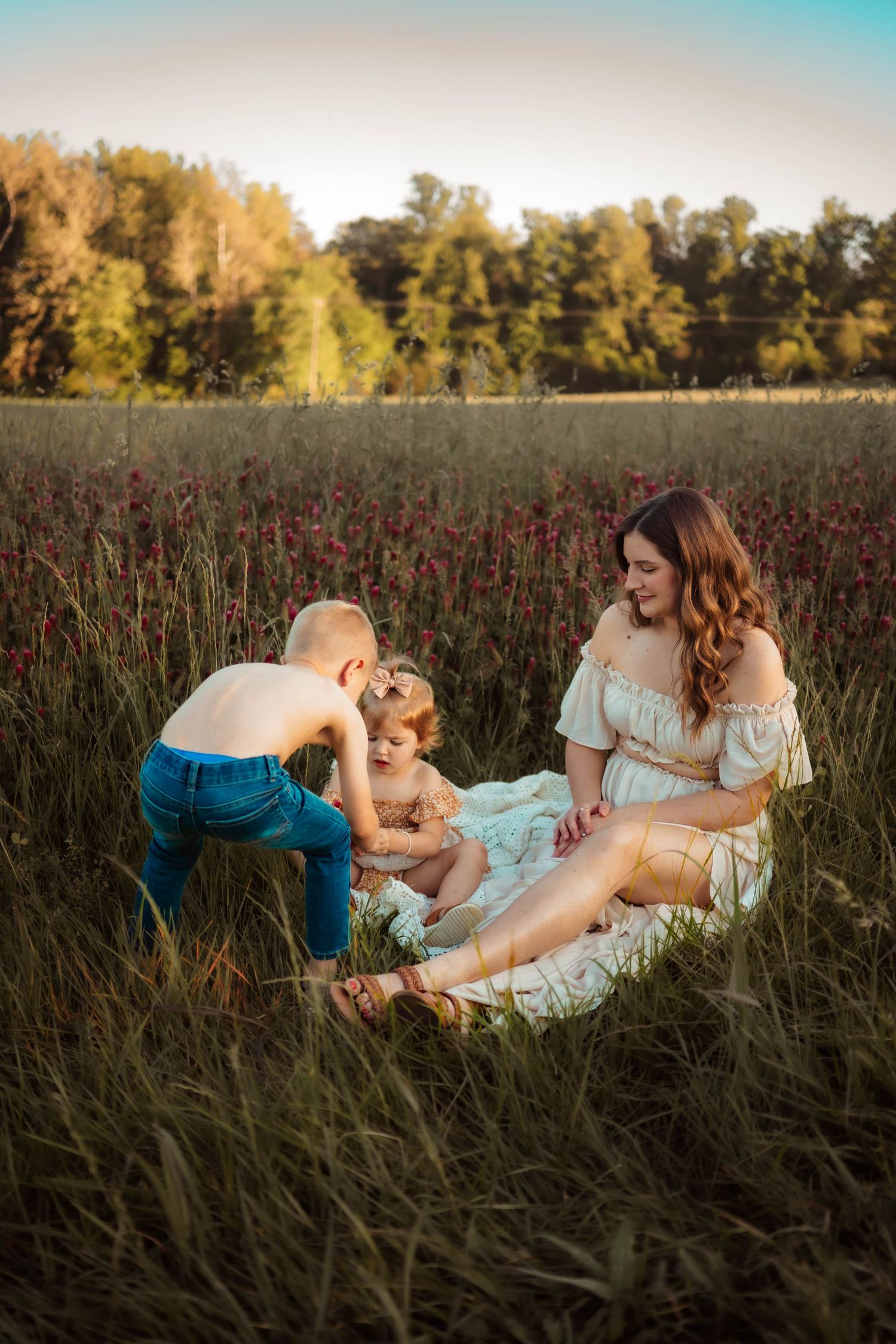 A playful family photoshoot in a rustic field with tall grass and natural lighting.