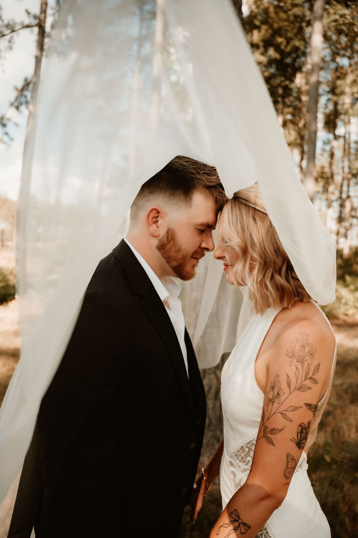 Intimate wedding portrait with white backdrop and pine trees.