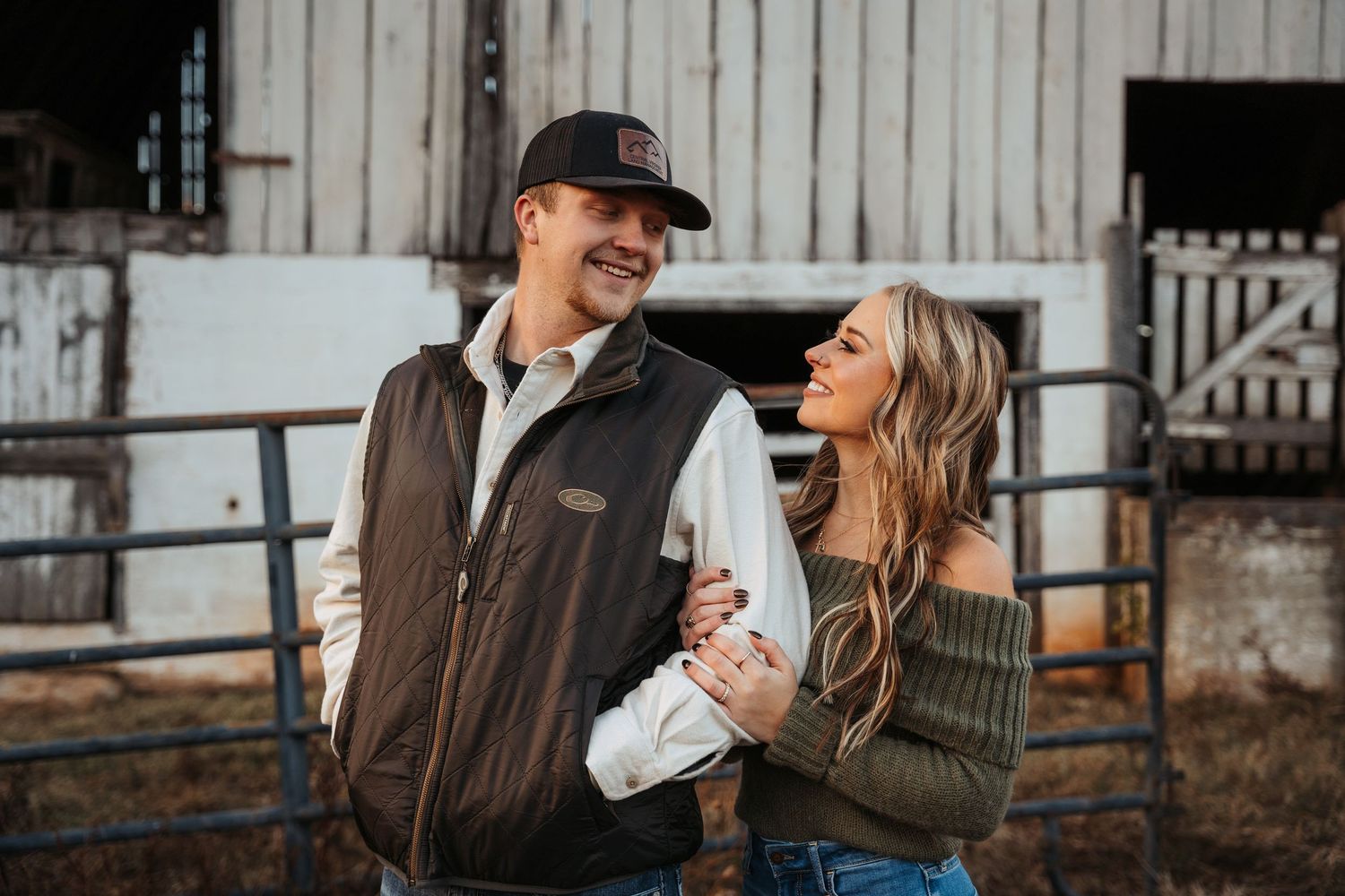 Couple sharing intimate moment outside rustic barn setting.