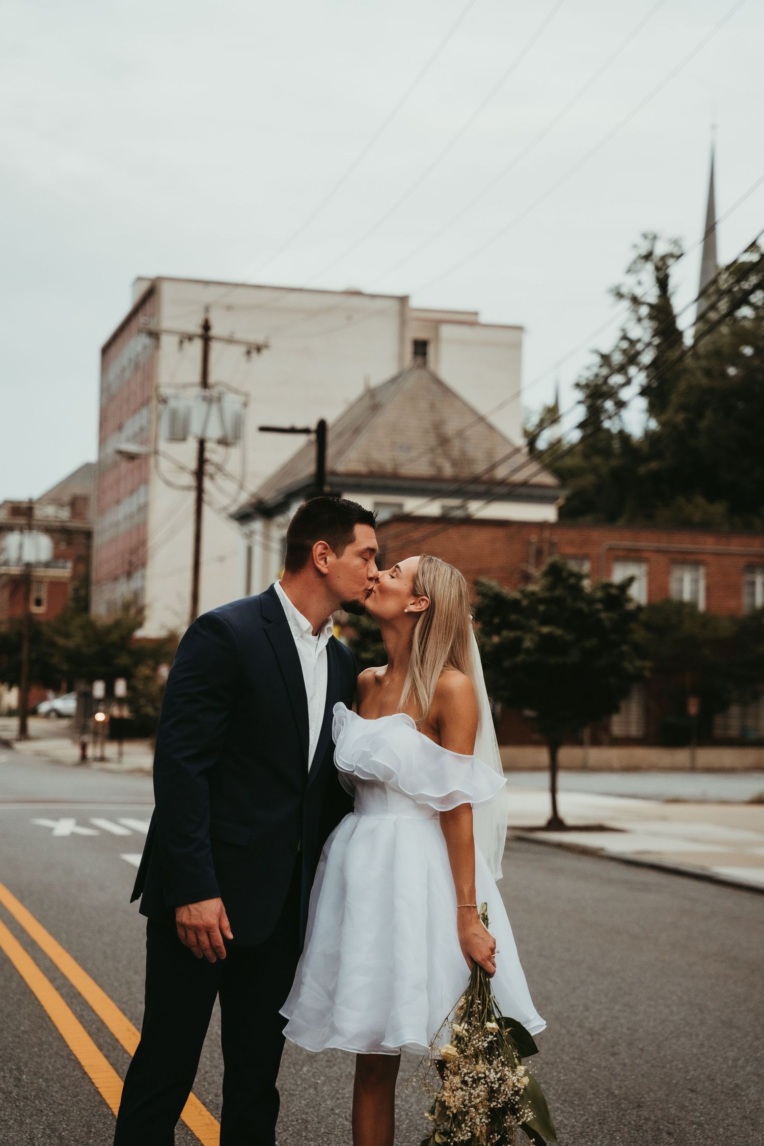 Urban wedding photography session on a city street with vintage buildings in background.
