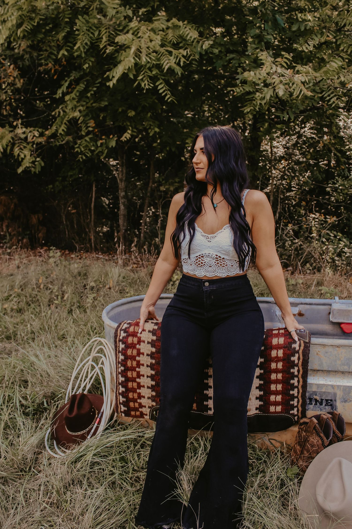Casual western-styled portrait with stock tank, rope, and patterned blanket outdoors.