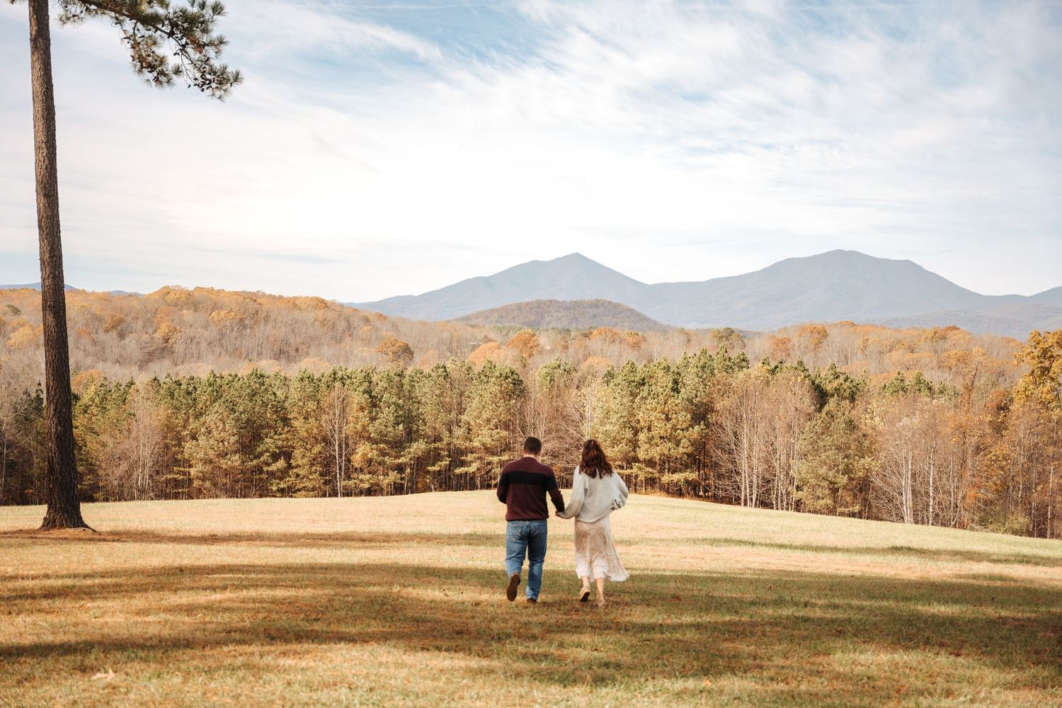 A couple walking together on a hilltop overlooking mountain views.