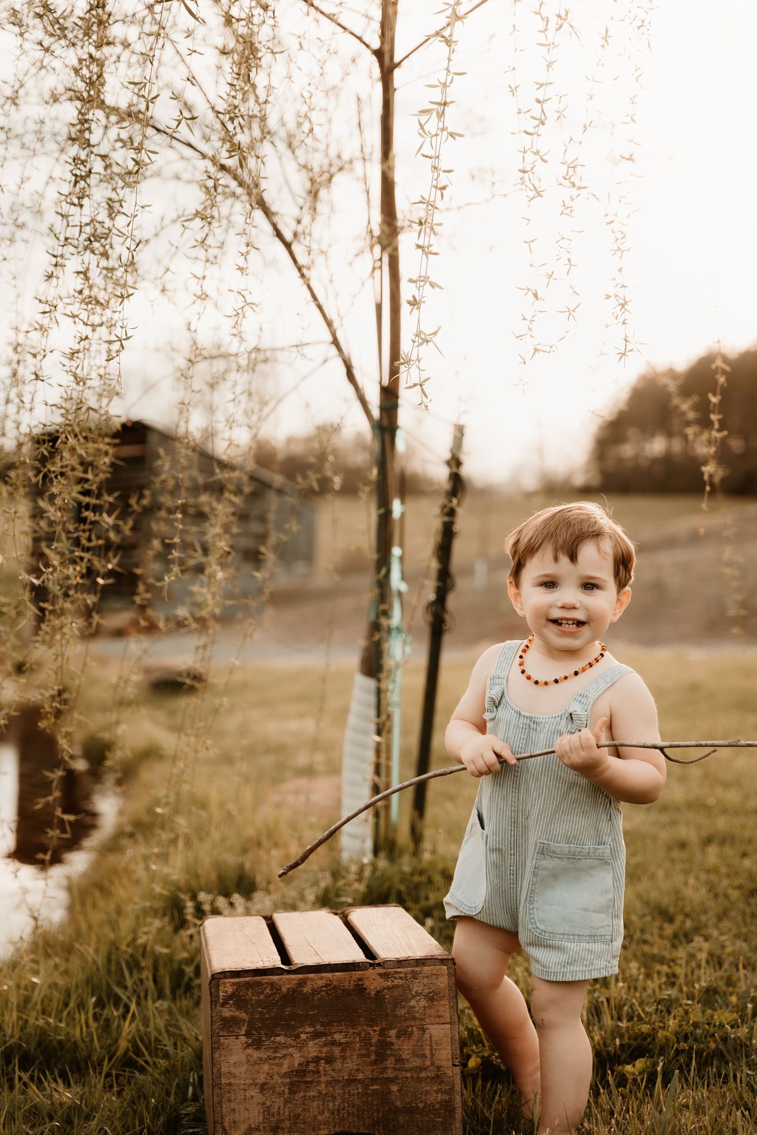 Child sitting on vintage wooden crate in rustic outdoor setting.