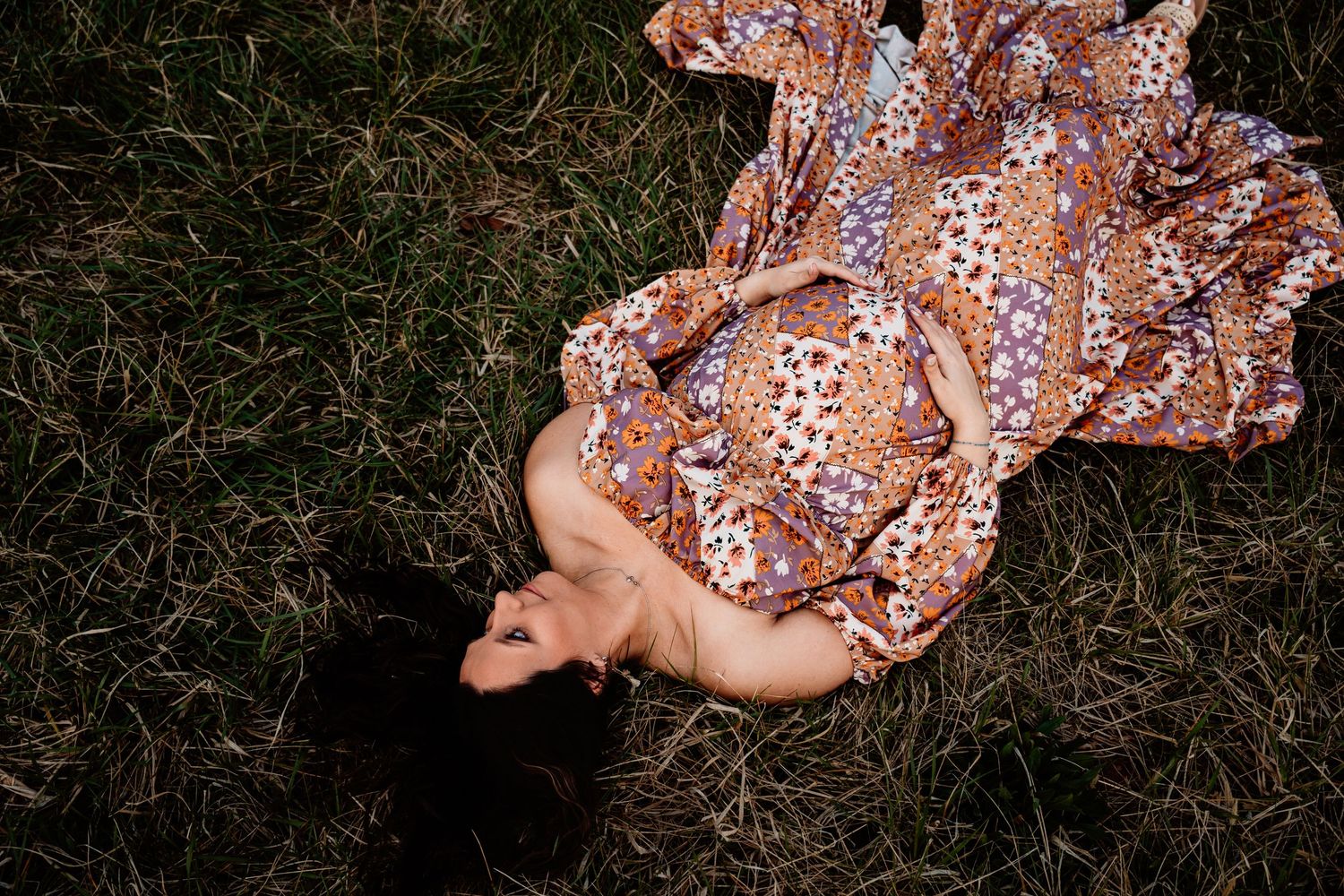 A floral patterned dress flows across grass in a dreamy overhead shot at sunset.