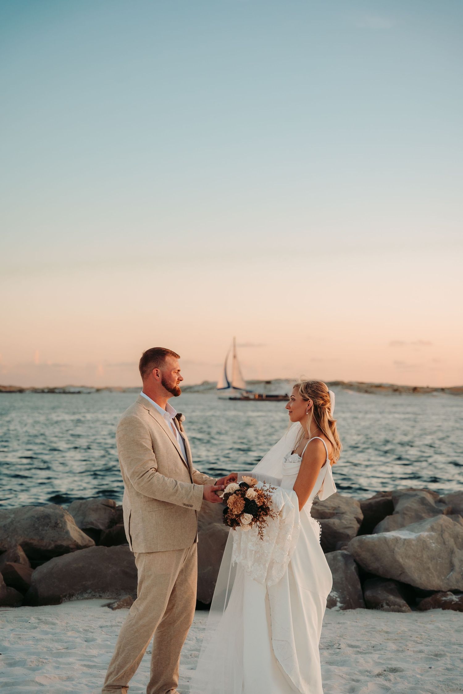 Seaside wedding portraits with rocky coastline and ocean views at golden hour.