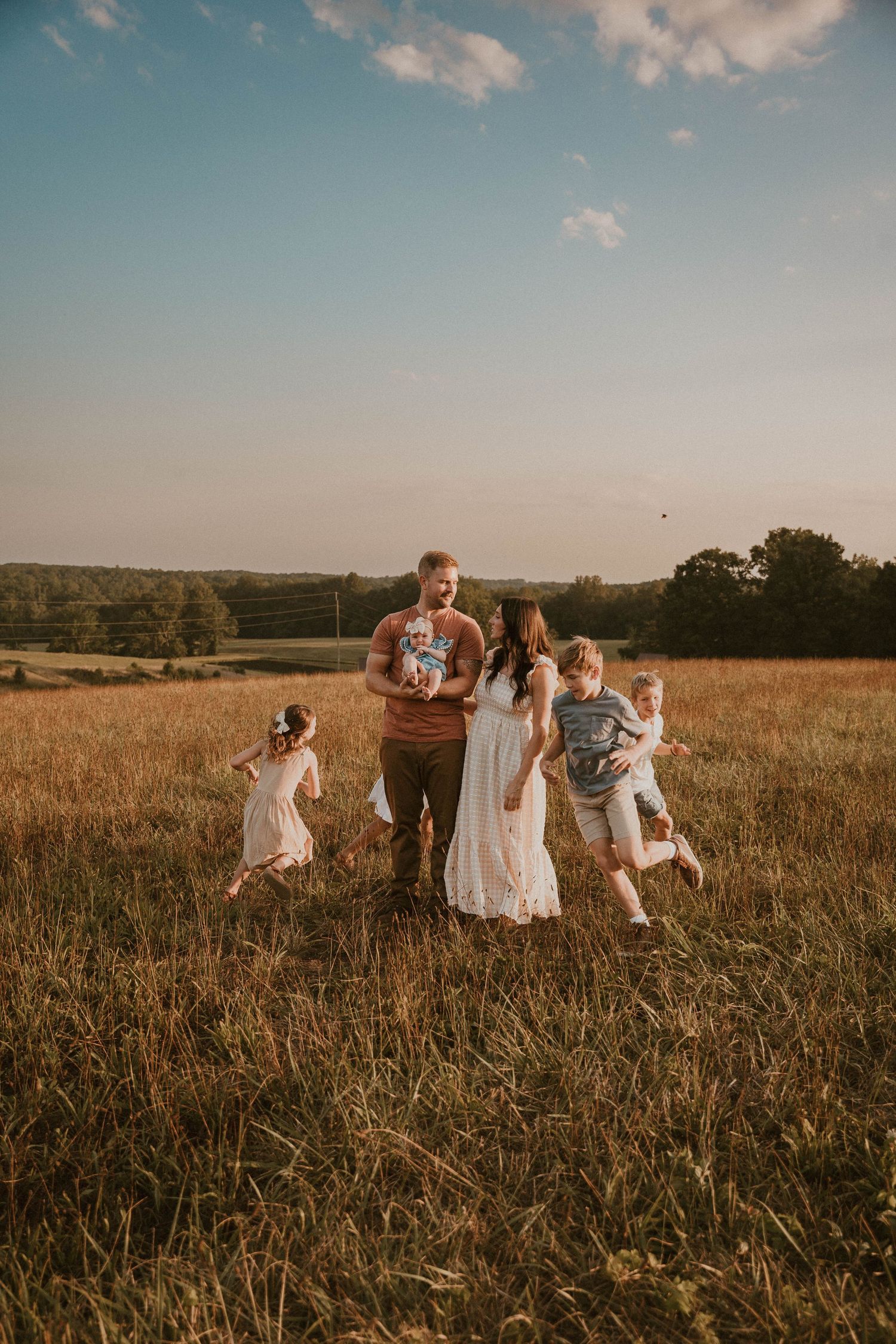 Family playing together in a sun-drenched meadow during golden hour.