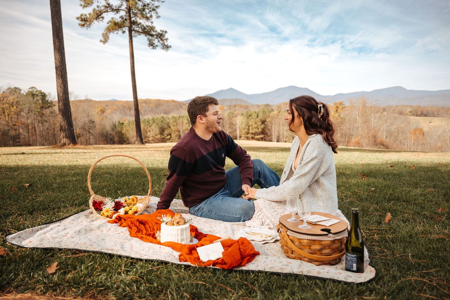 A romantic picnic setup with orange decor and mountain views in the background.