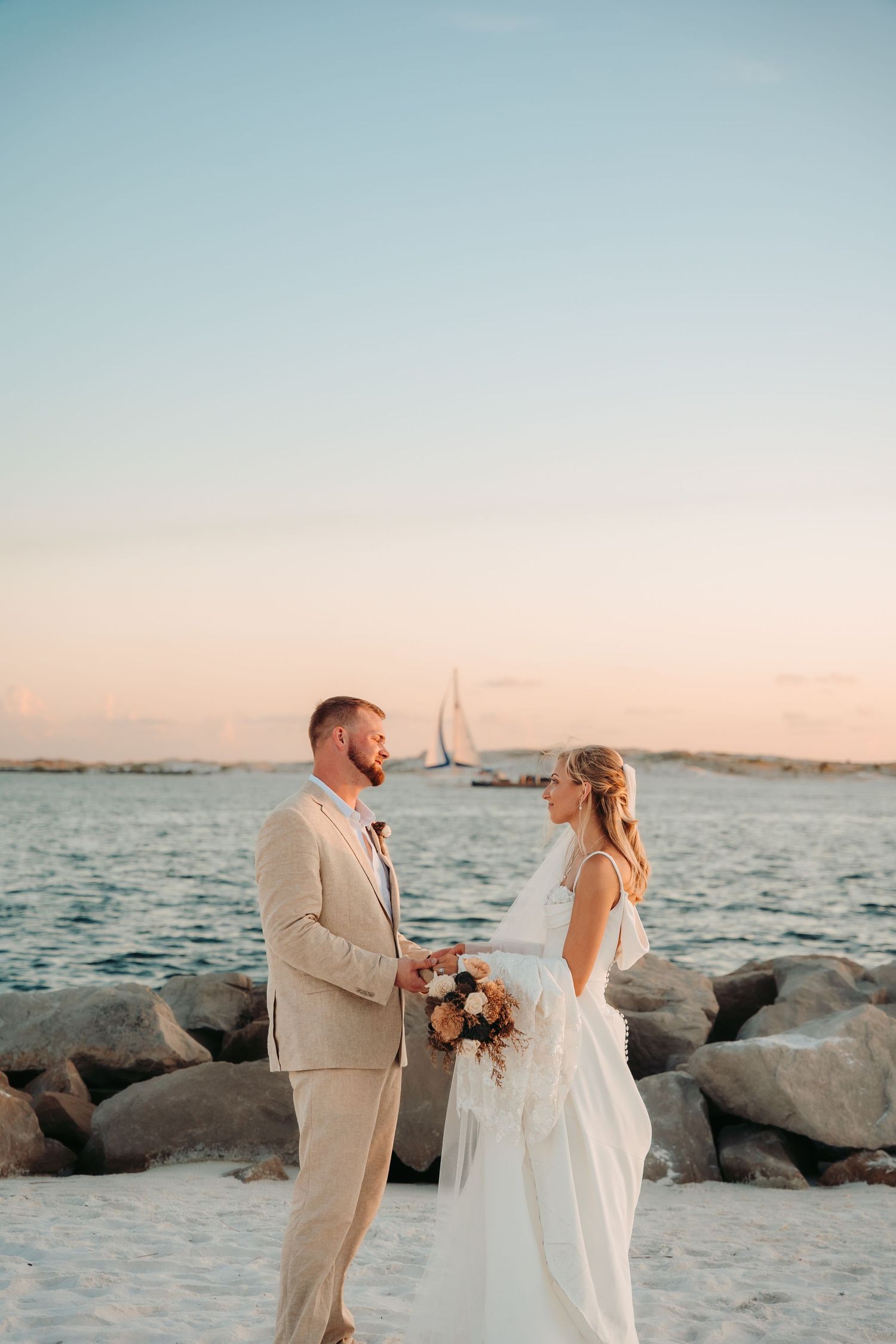 Beachside wedding portraits at sunset with couple on rocky coastline.
