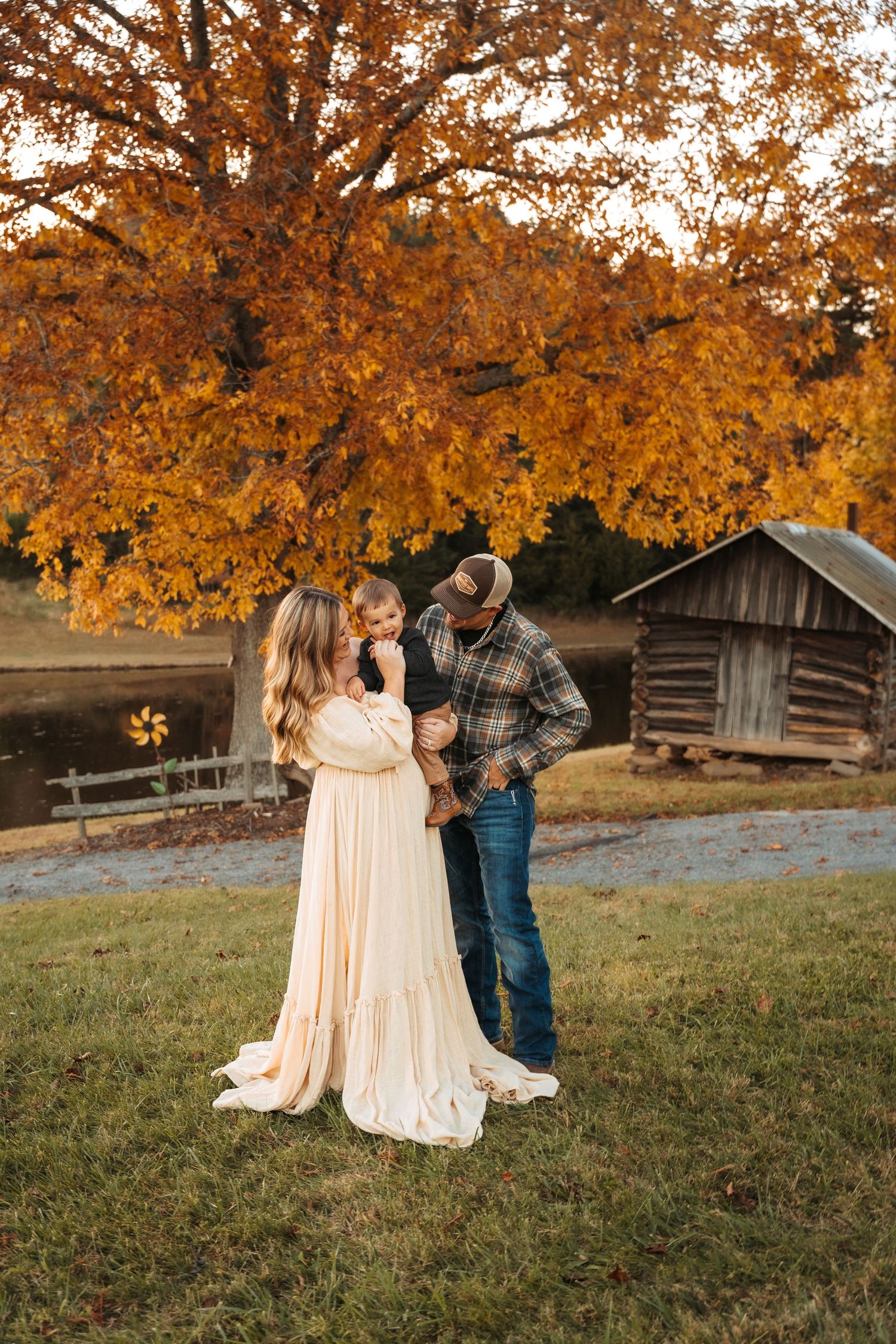 Autumn family photoshoot with beautiful golden foliage and rustic cabin in background.