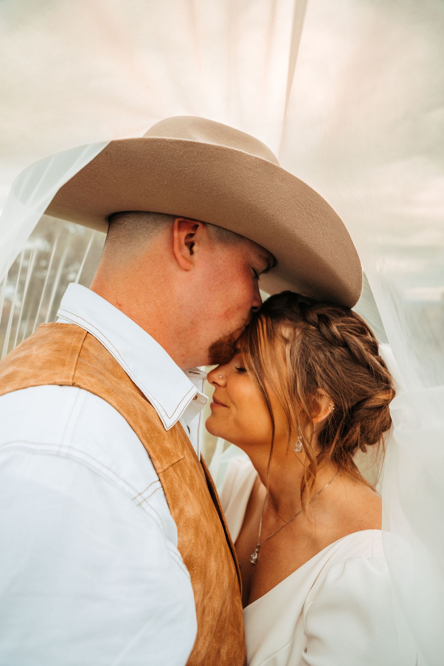 Intimate close-up of couple in western wedding attire sharing romantic moment.