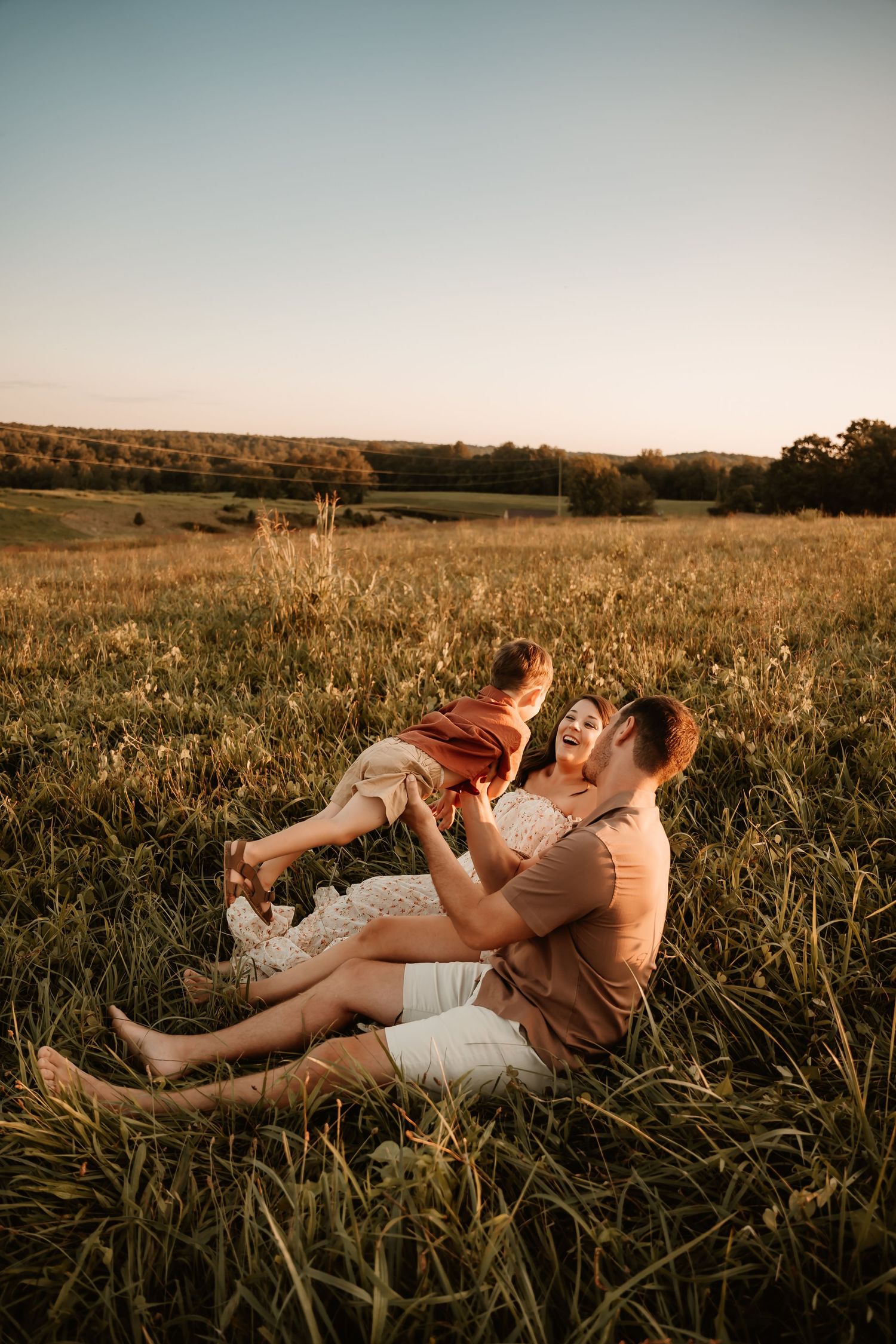 Family lying together in tall grass during sunset photography session.