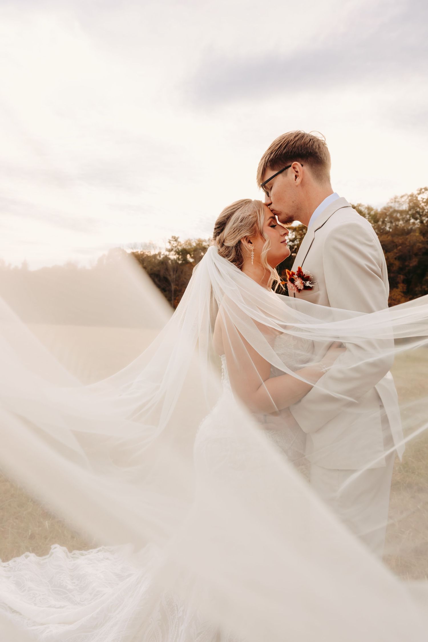Intimate wedding portrait with flowing veil catching the breeze during golden hour.