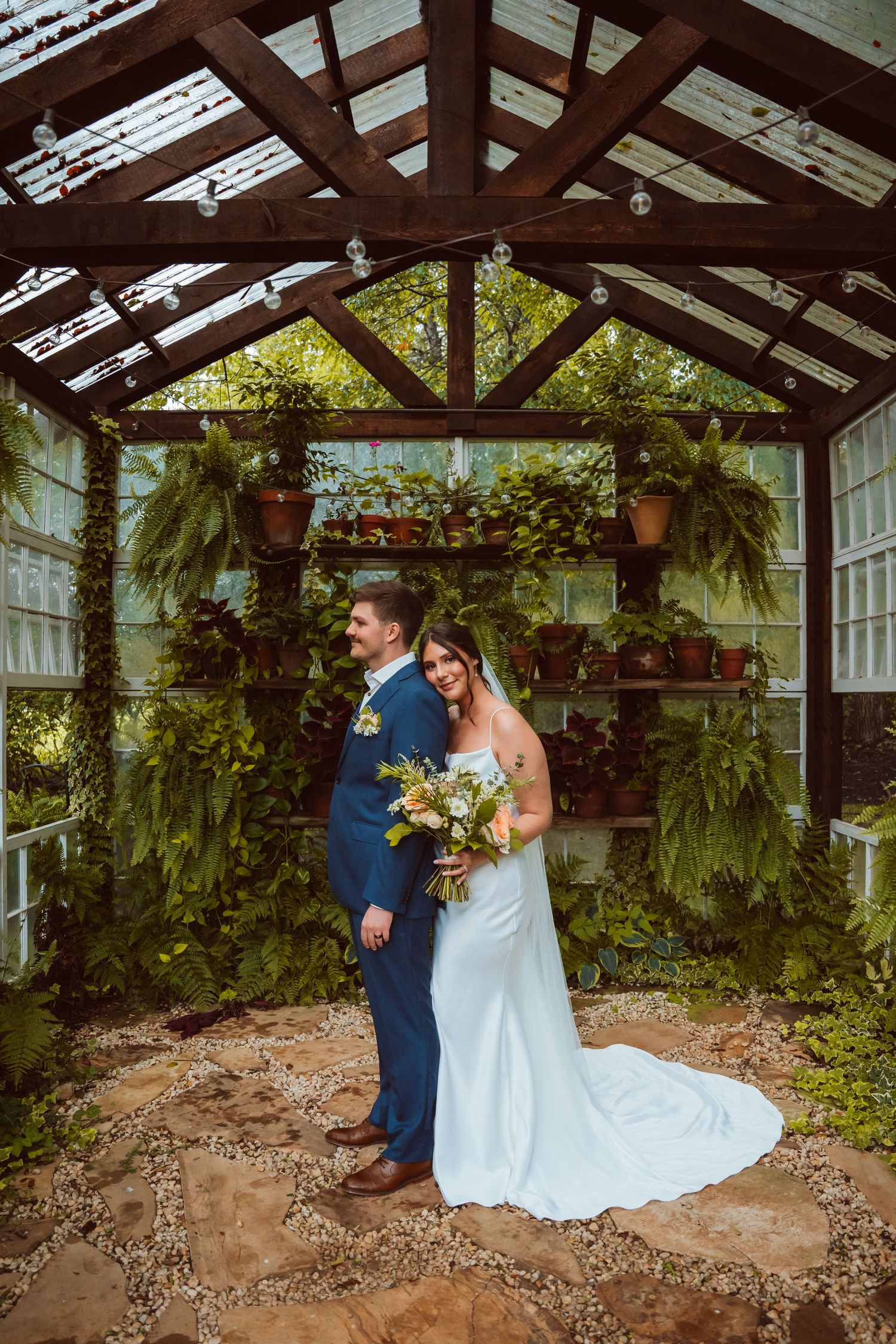 Indoor greenhouse wedding venue with exposed beams and hanging plants.