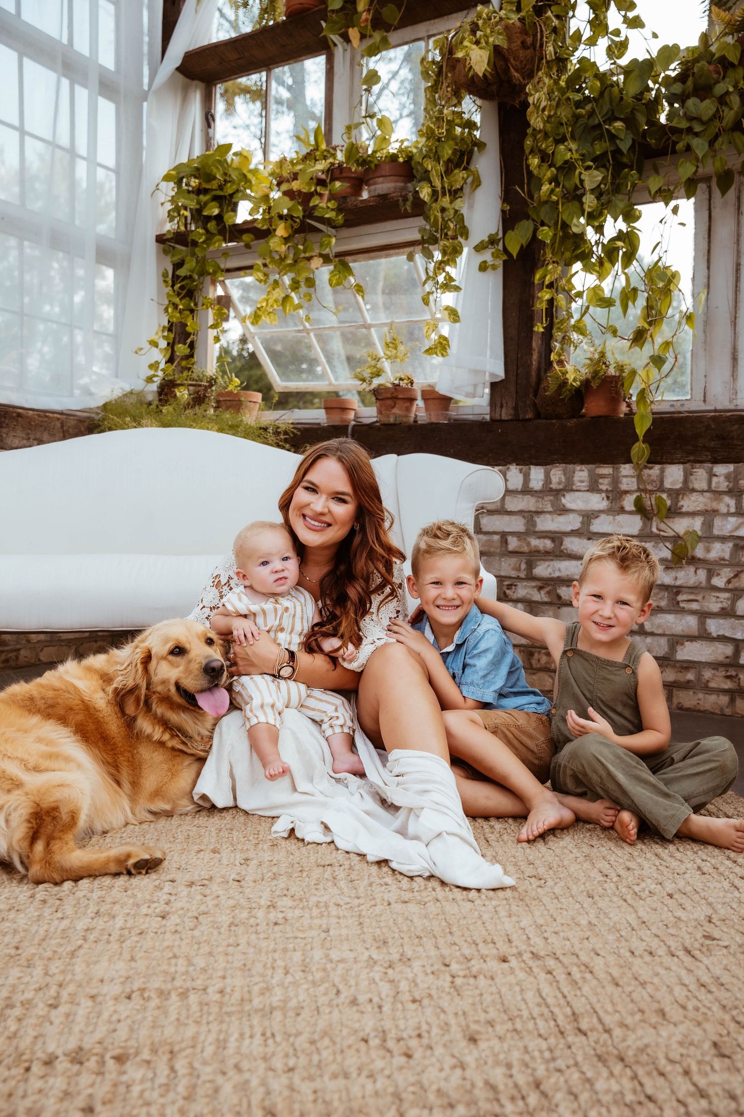 Indoor family portrait with a golden retriever by a window with climbing vines.