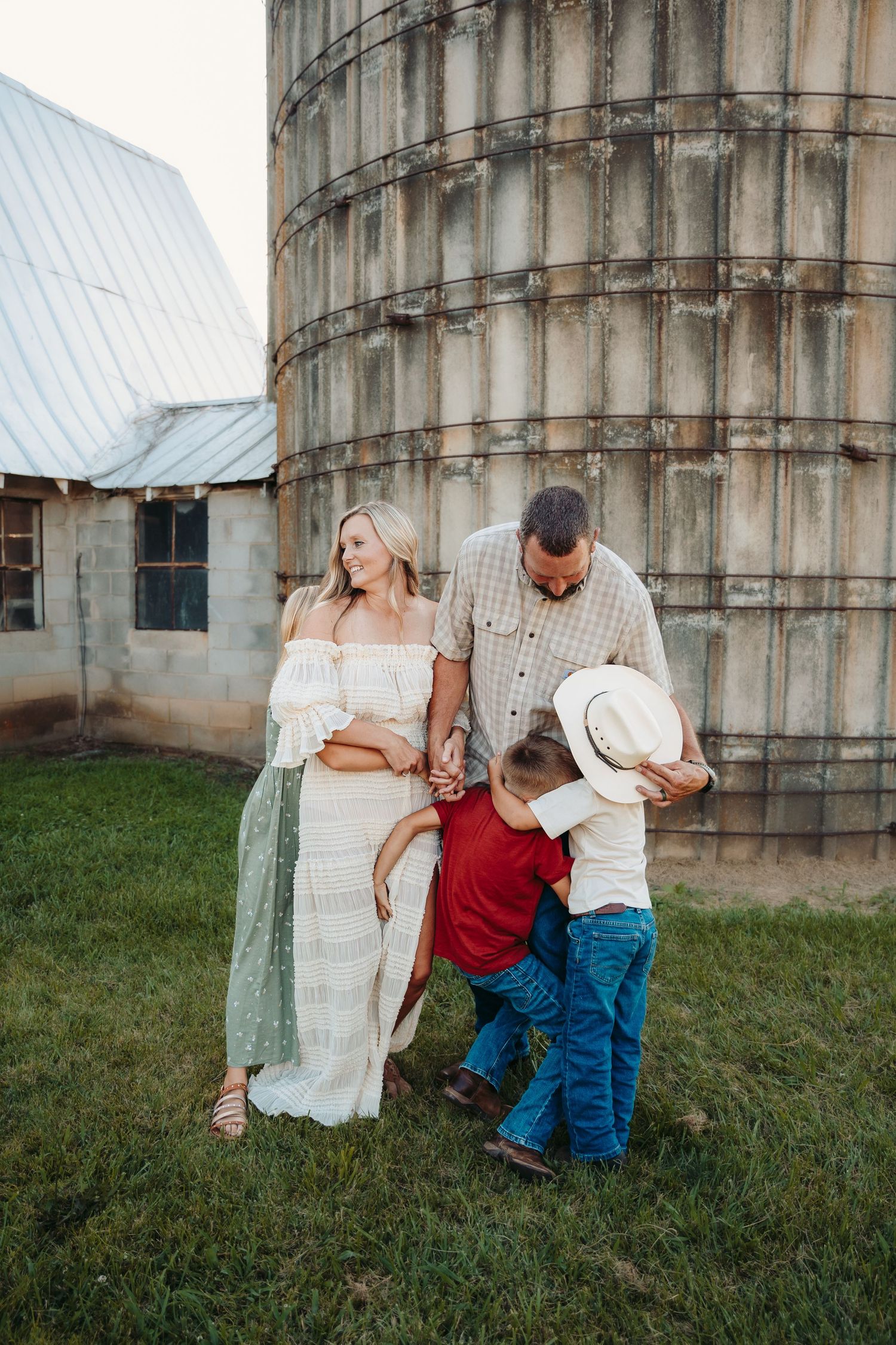 Family photos taken against rustic grain silo in countryside setting.