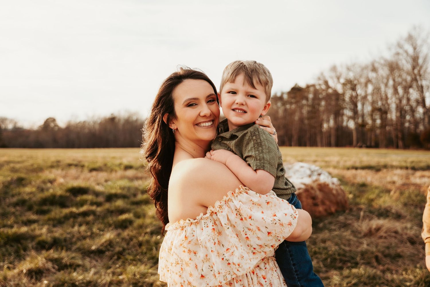 Mother and child share joyful moment together in golden field at sunset.