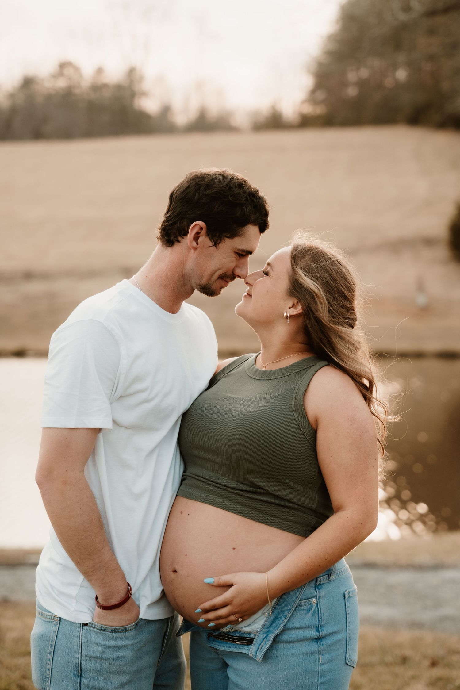 Intimate maternity couple photoshoot in casual attire during golden hour.