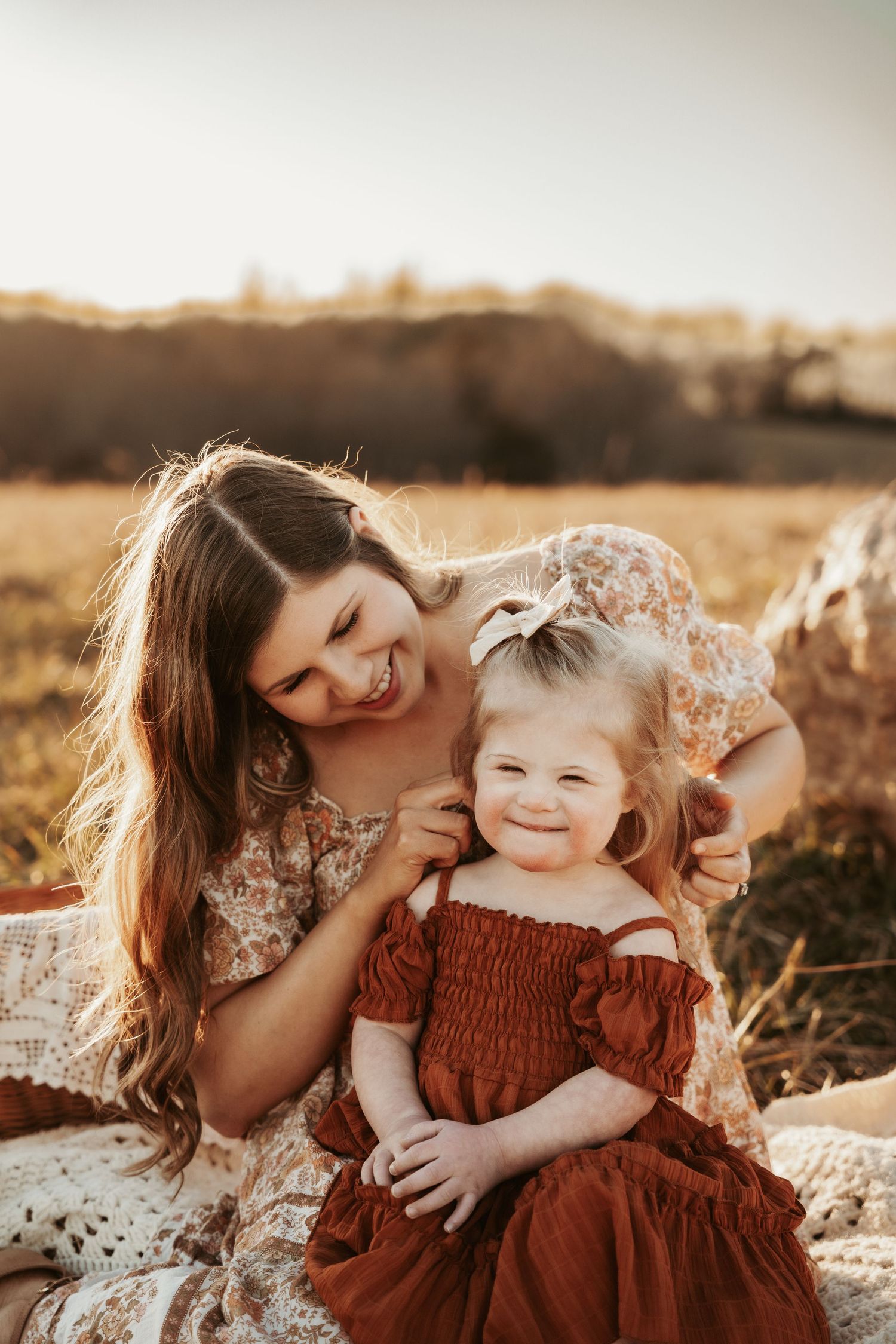 Mother and child share intimate moments in a golden field during sunset.