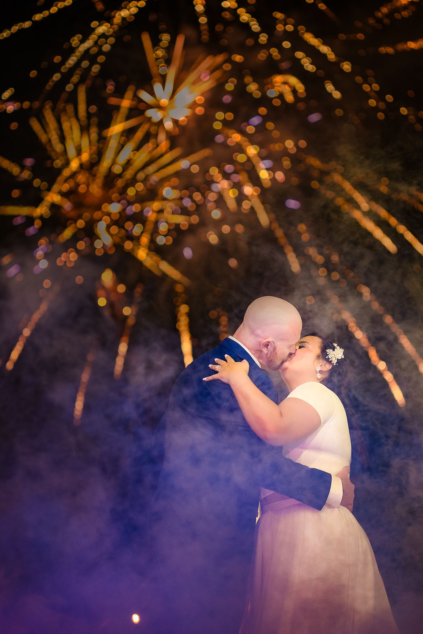 Couple dances under spectacular golden fireworks display at nighttime celebration.