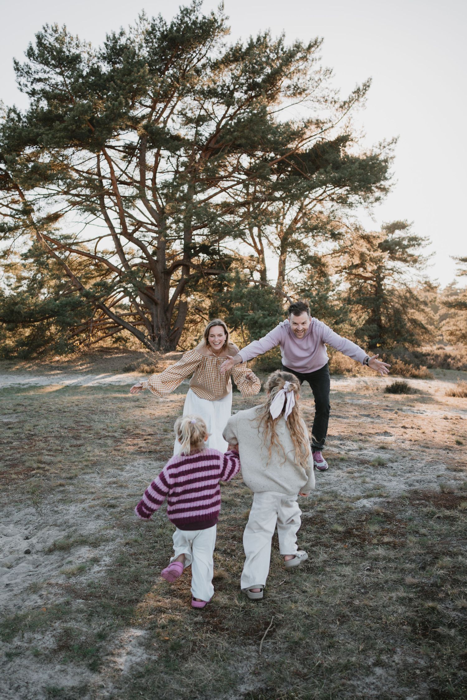 Sfeervolle gezinsfotografie in de natuur van Soest. Twee kinderen rennen enthousiast met open armen op hun lachende ouders af.