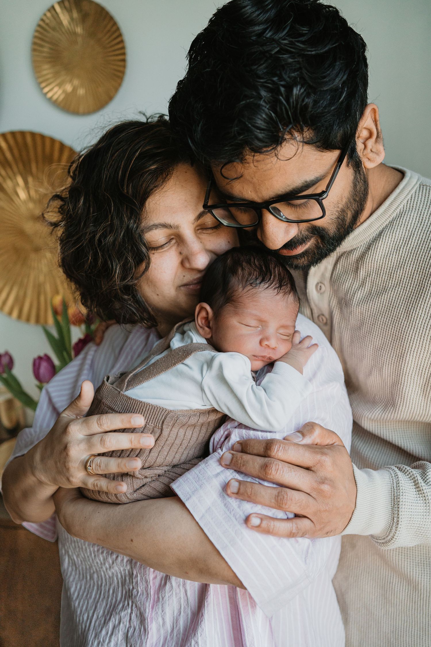 Newborn fotografie in Soest, Utrecht: een liefdevol koppel houdt teder hun slapende baby vast tijdens een newbornfotoshoot.