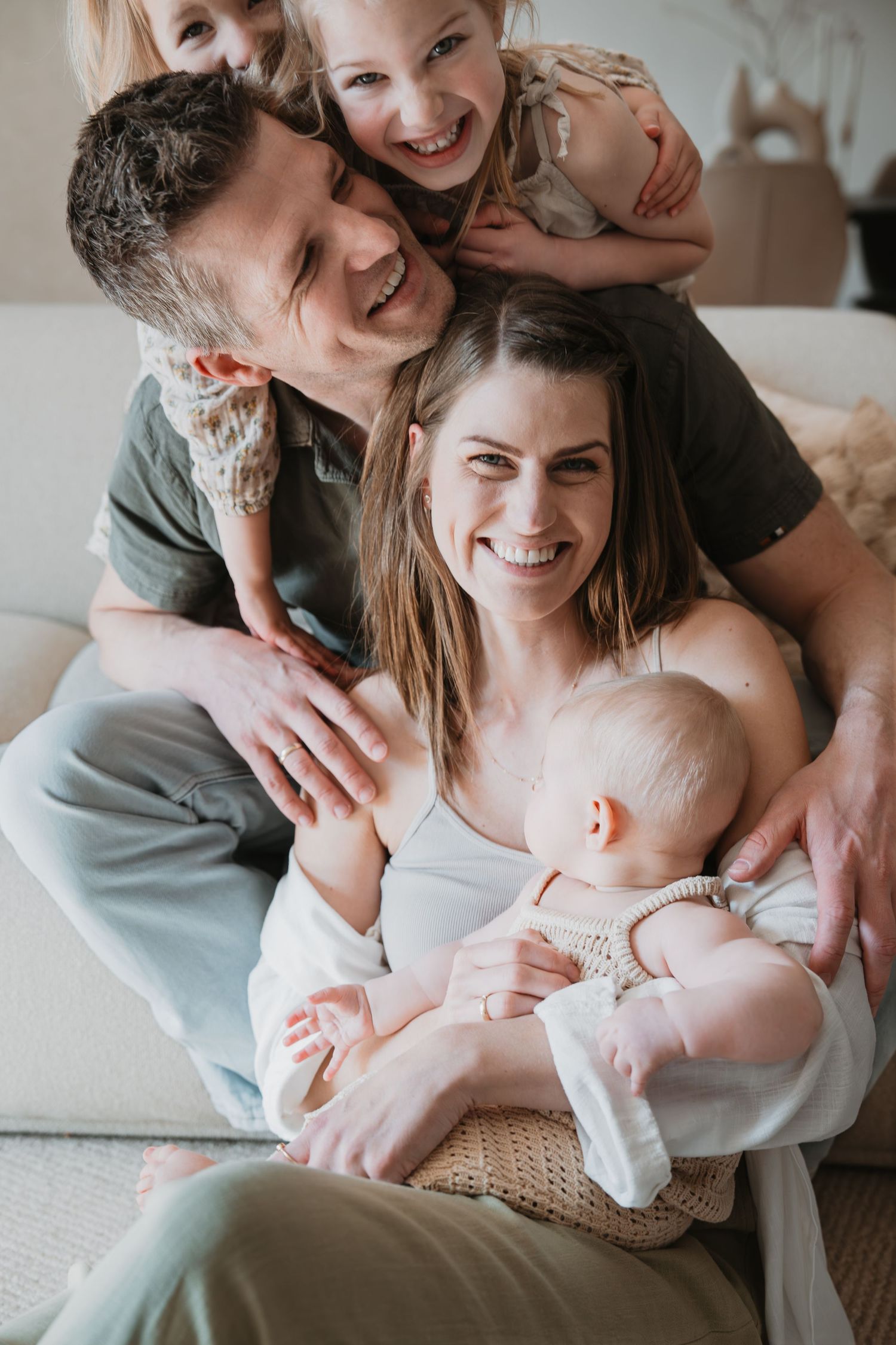 Gezinsfoto vol liefde: ouders en hun drie kinderen (inclusief baby) lachen naar de camera tijdens een fotoshoot binnen. Gezinsshoot in Soest
