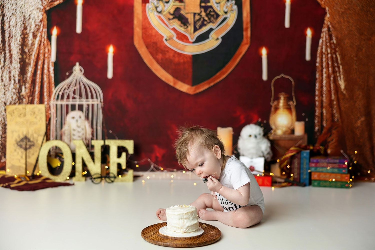 Baby's first birthday cake smash with Harry Potter theme, featuring Hogwarts backdrop, owl, candles, and ONE sign.