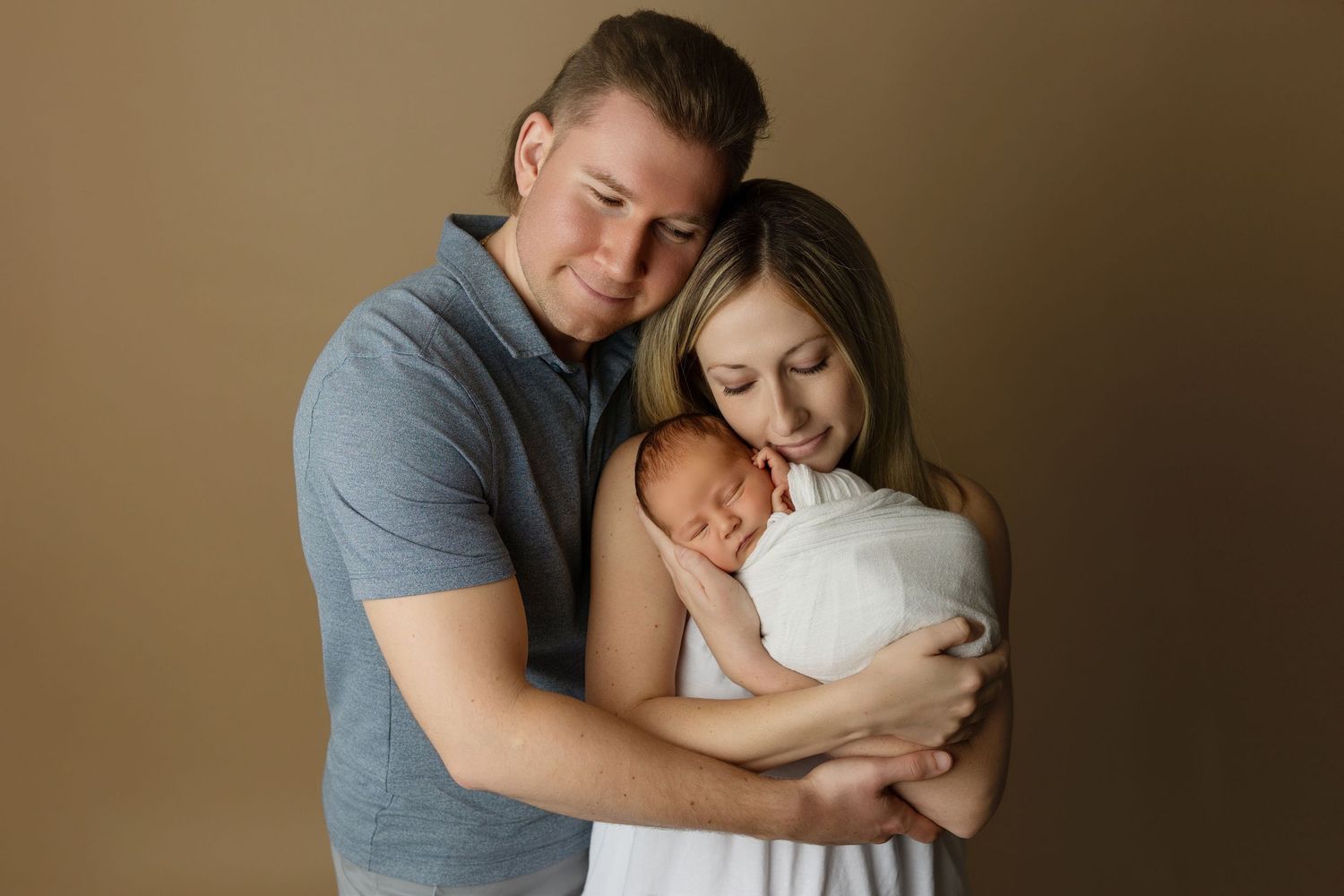 Intimate family portrait with newborn in warm studio setting.