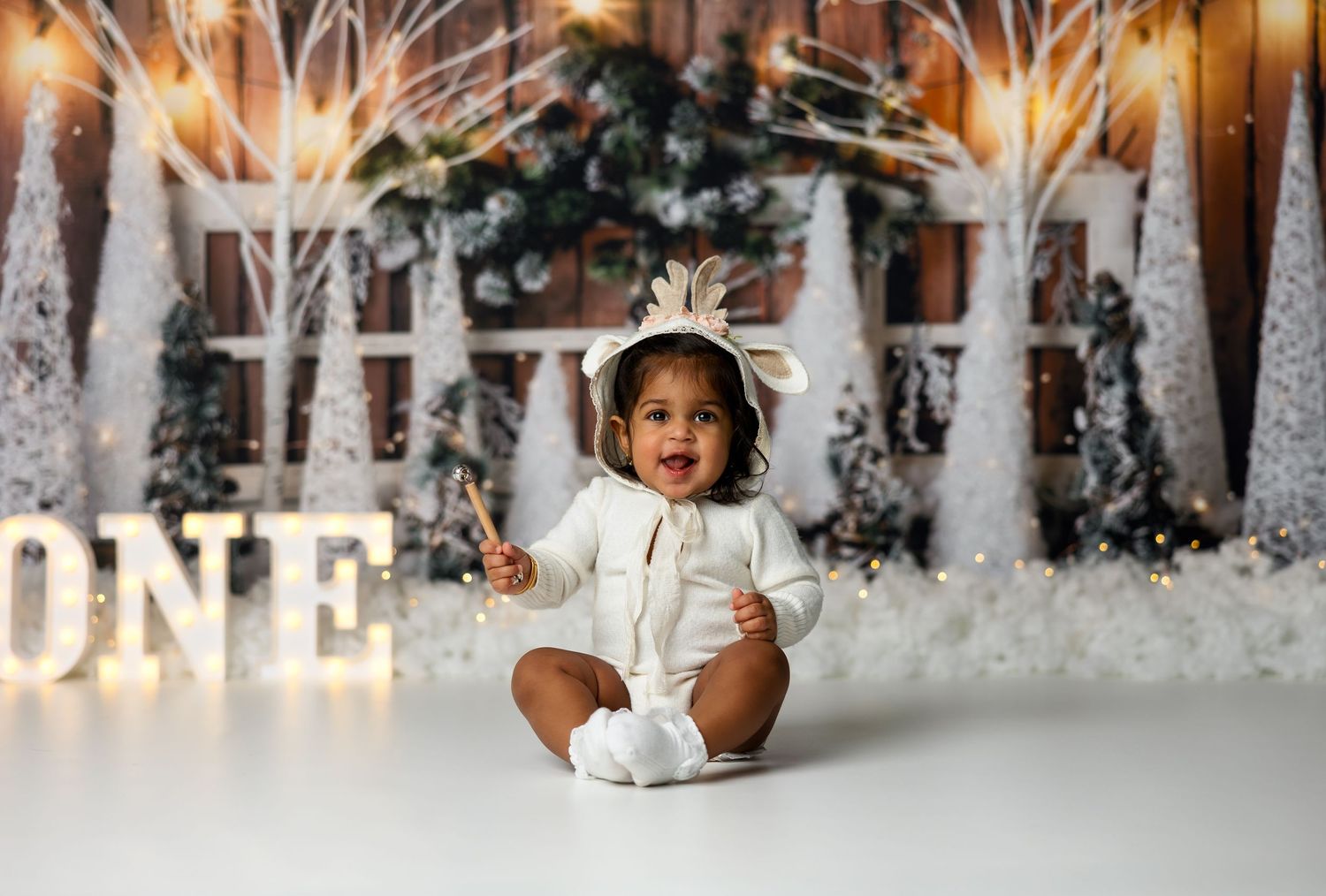 Winter woodland scene with snowy trees and twinkling lights for first birthday celebration.