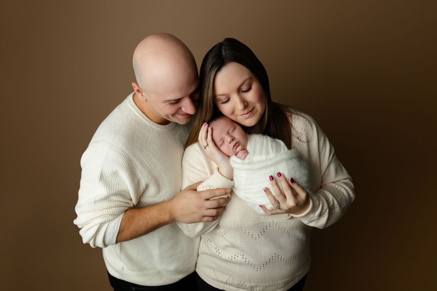 A series of intimate lifestyle maternity photos of a couple in cream colored sweaters showing different tender poses.