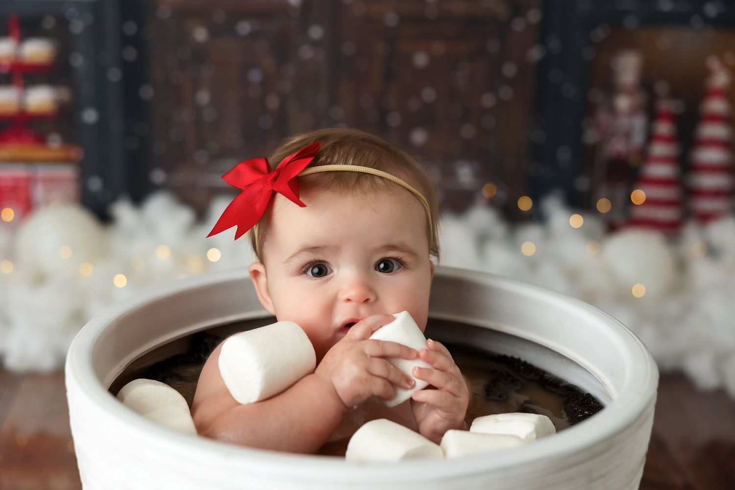 A white ceramic mug filled with hot chocolate and marshmallows against a festive Christmas backdrop.