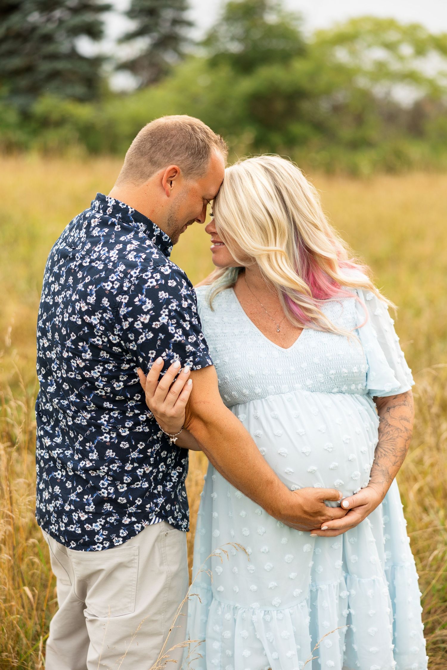 A romantic moment between partners in a summer meadow with matching floral and white outfits.