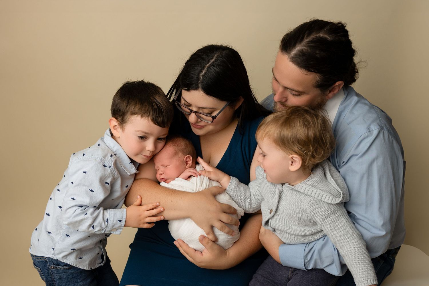 Indoor family portrait with neutral background and casual styling.