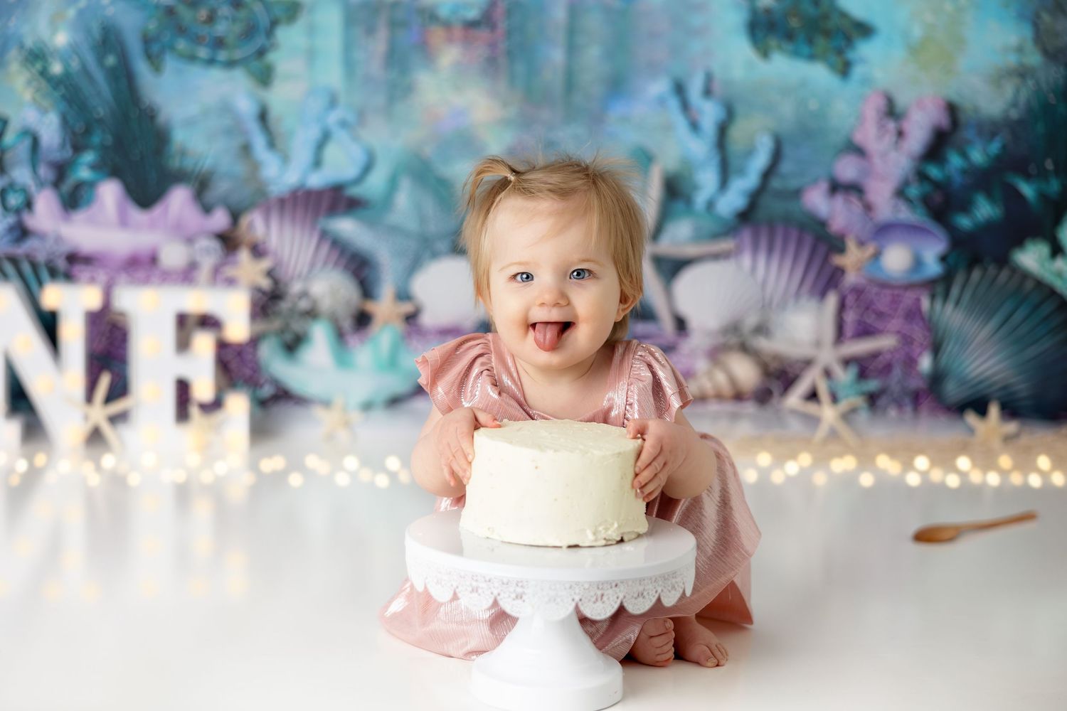 Joyful birthday celebration with cake and underwater themed backdrop featuring seashells and castle.