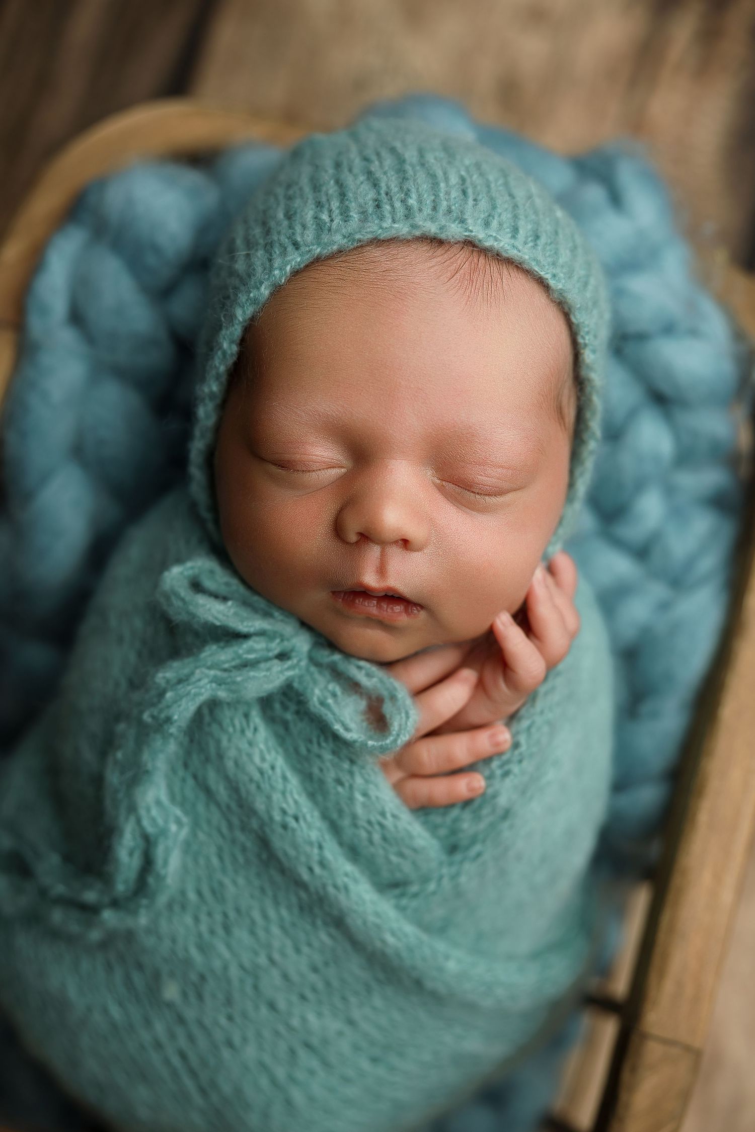 Close up shot of a newborn baby tucked into a warm cozy swaddle during a mini photography session.