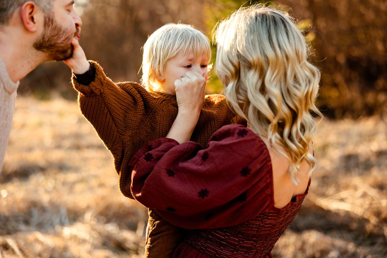 A tender family moment captured during golden hour in a rustic outdoor setting.
