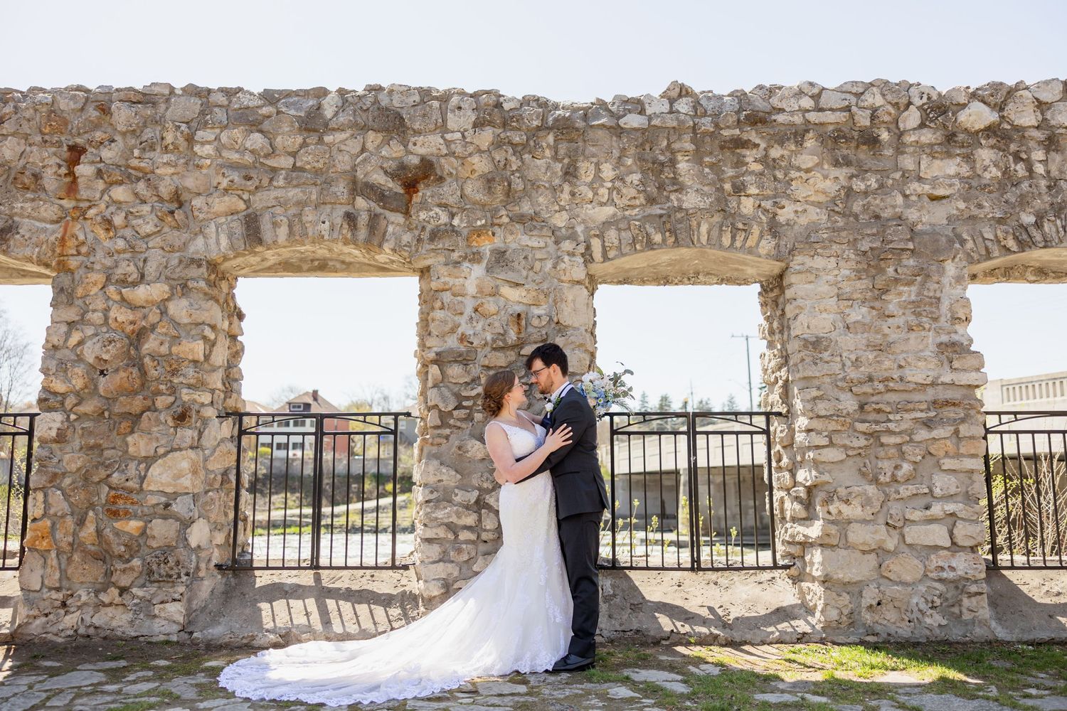 Wedding portrait framed by historic stone archways with long train dress.