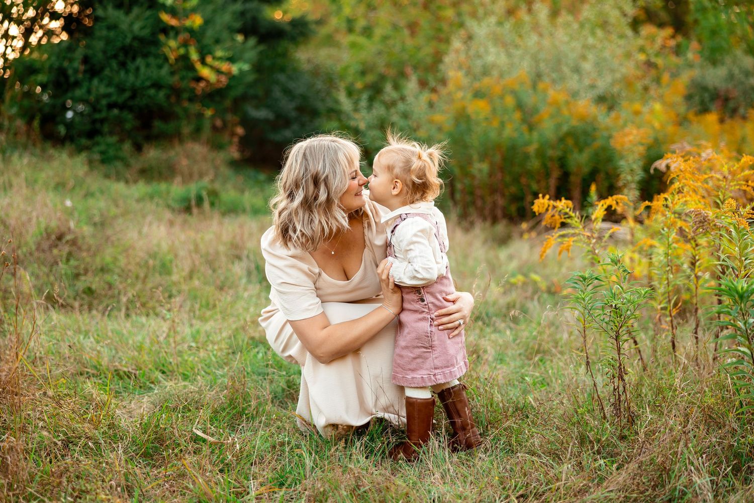 A tender moment shared between parent and child in a sunlit autumn meadow with golden wildflowers.