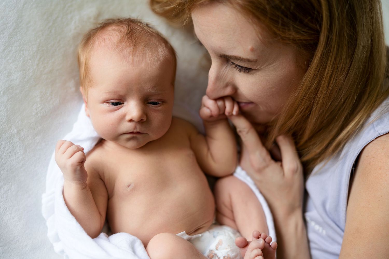 Monochrome images show tender moments between parent and newborn in intimate indoor portrait settings.