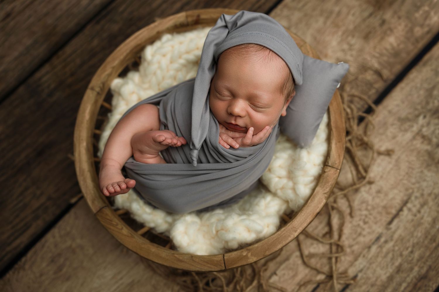 Sweet newborn smiling while wrapped tightly during an affordable Keepsake Mini Session in Brantford.