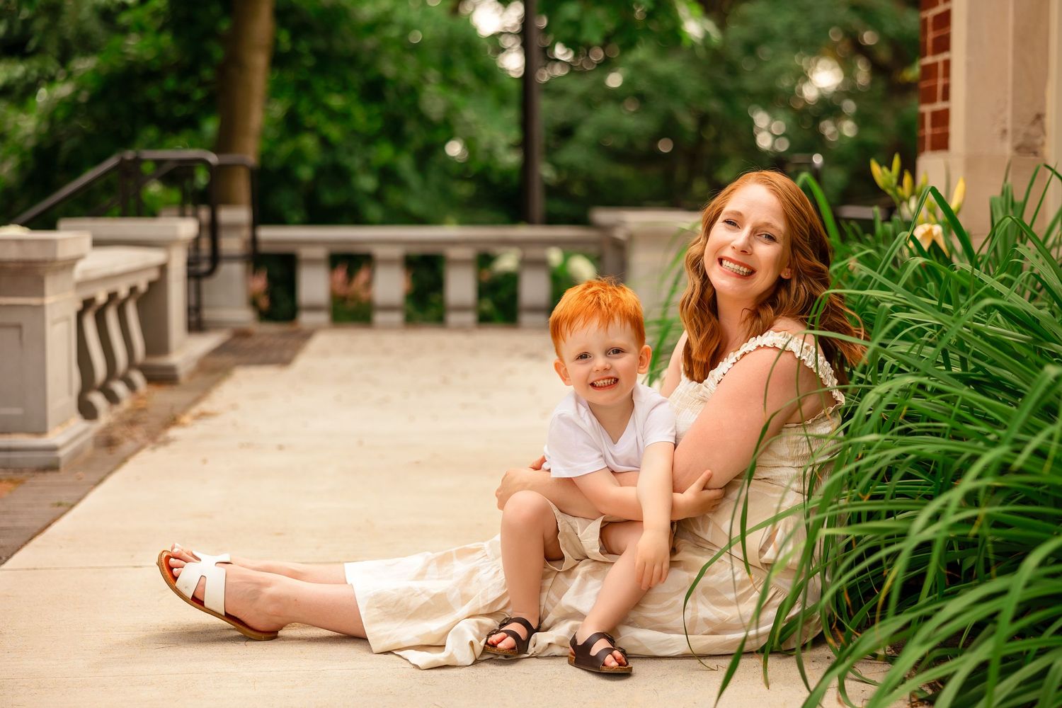 A relaxed outdoor portrait session on a stone patio with lush green plants.