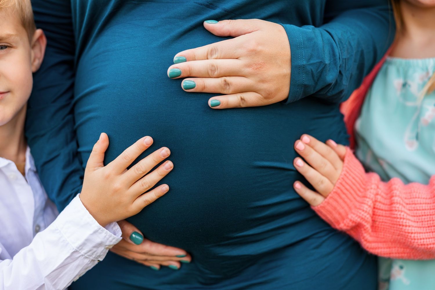 A maternity photo shoot in a casual style with people wearing blue and white outfits against a natural backdrop.