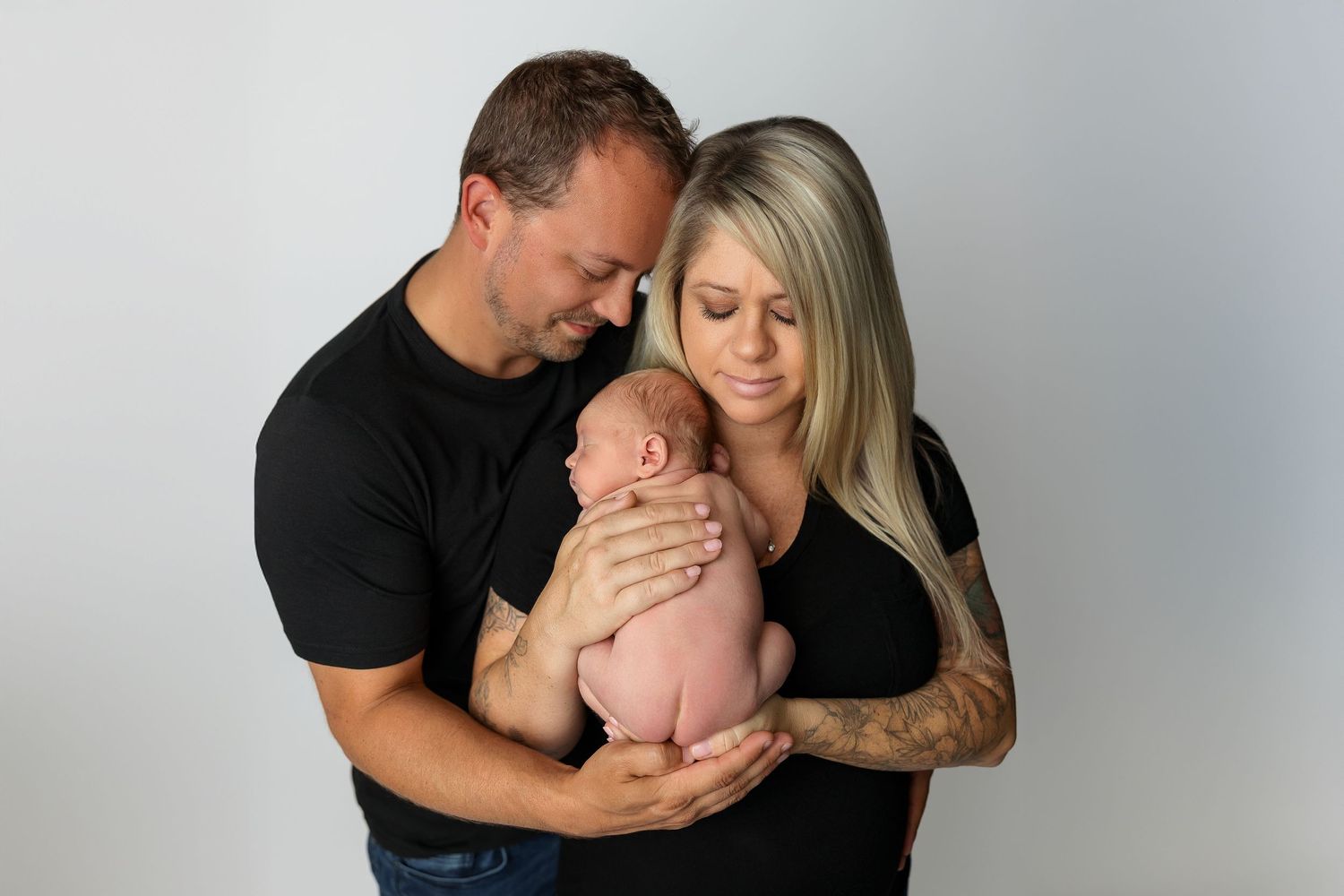 A series of tender family moments showing parents sharing loving kisses with their baby against a neutral backdrop.