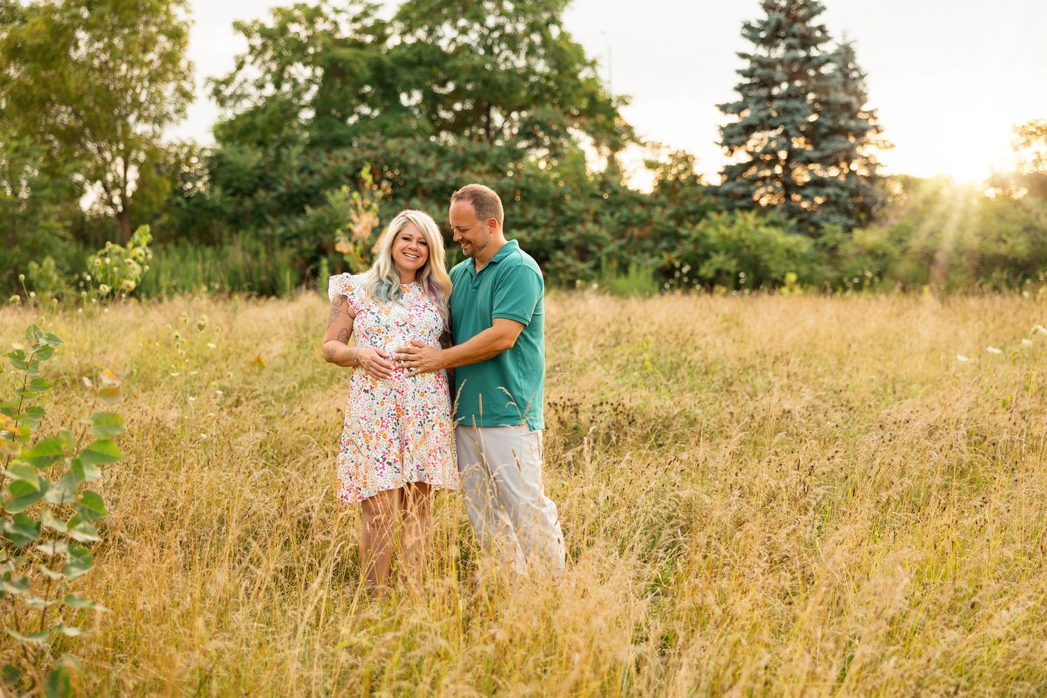 Sweet romantic couple poses and laughs together in a sun-drenched meadow at sunset.