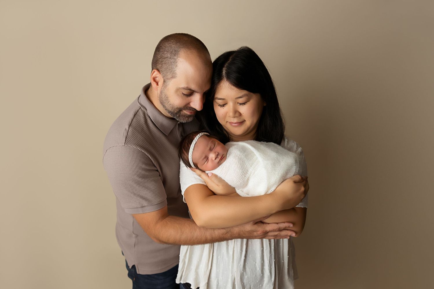An intimate family moment captured against a beige studio background.
