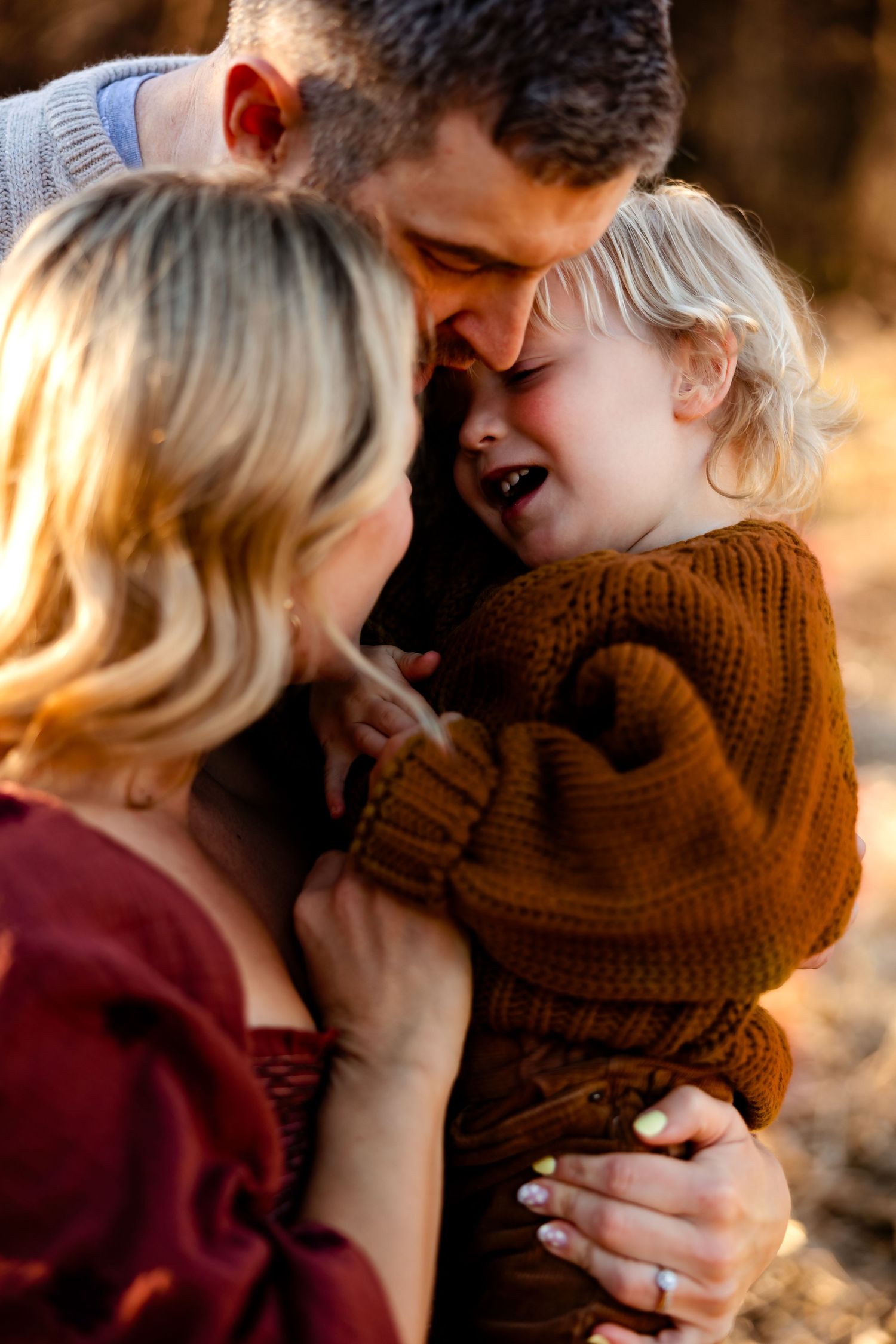 A heartwarming family moment sharing laughter and cuddles in golden sunlight.