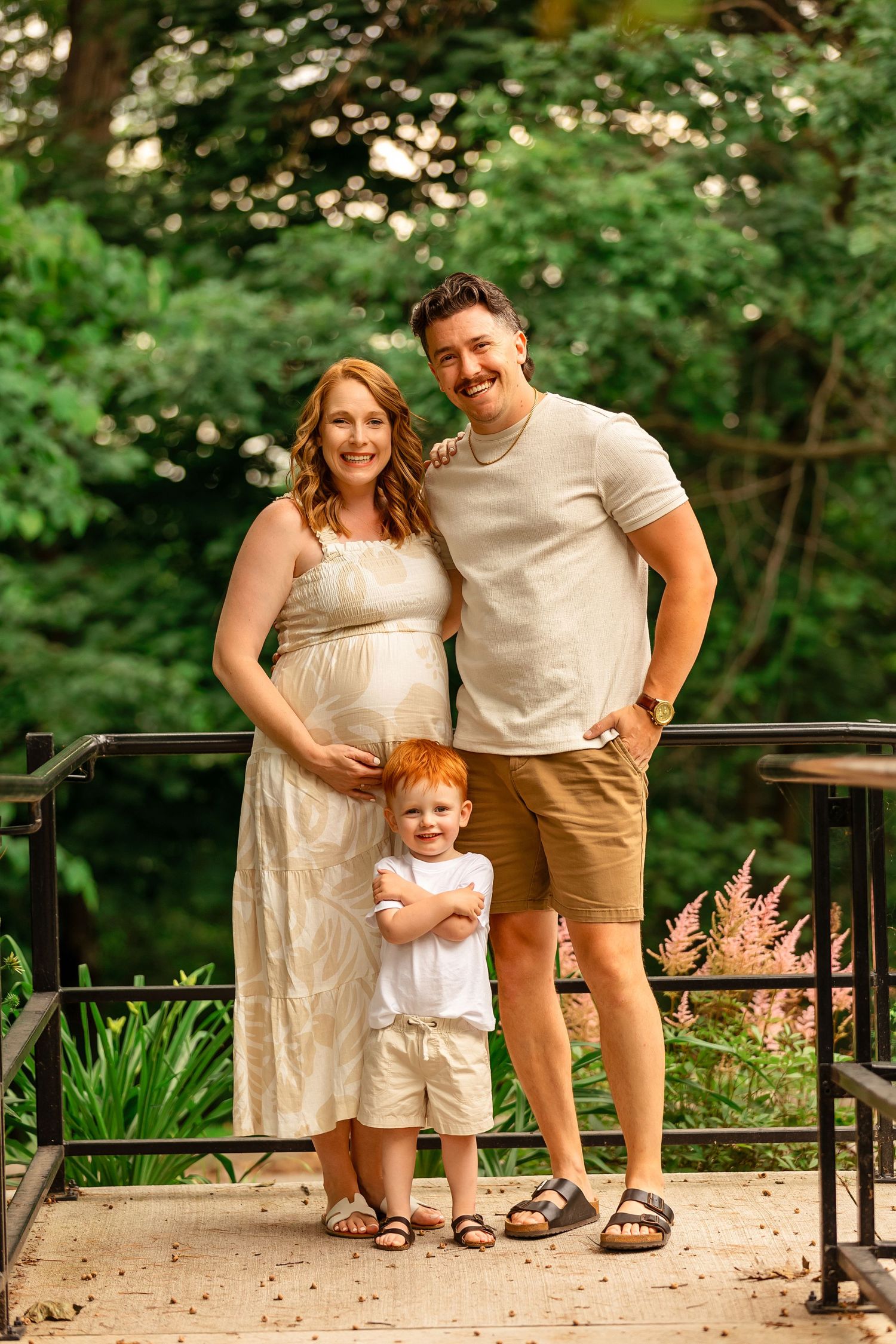 A summer family portrait session on a garden path with lush greenery in the background.