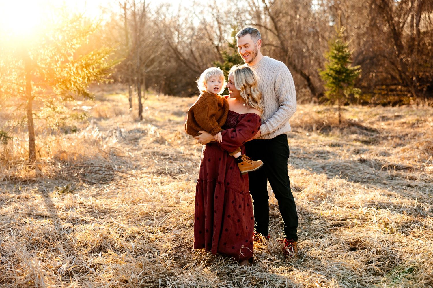 Family standing together in autumnal setting with golden hour lighting.
