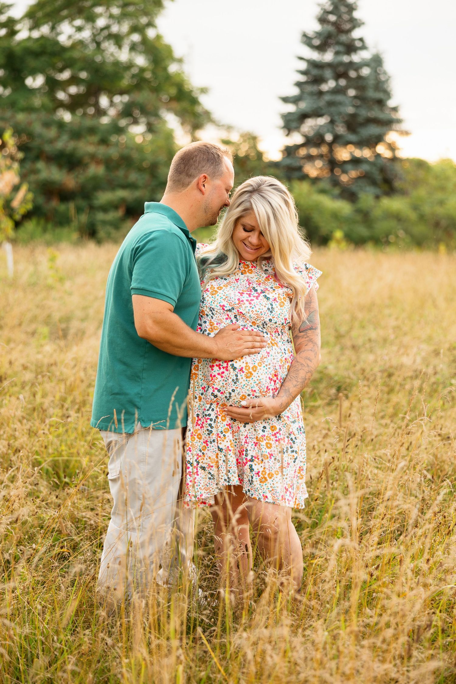 A couple shares intimate moments in a sun-drenched field of tall grass during golden hour.